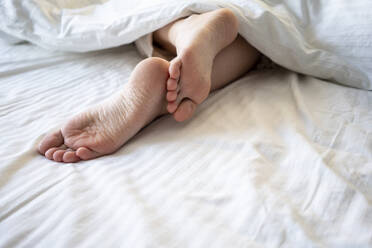 Young woman legs in blanket on bed at home - VPIF03752