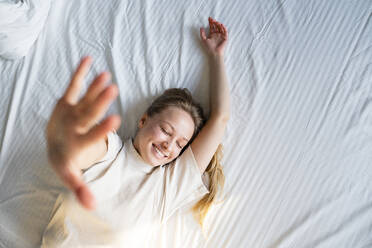 Junge Frau gestikuliert auf dem Bett liegend - VPIF03758