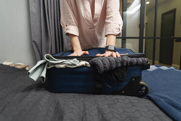 Frau packt zu Hause Kleidung in einen Koffer - VPIF03812