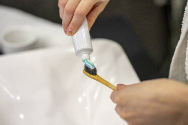 Woman taking toothpaste on toothbrush at home - VPIF03822