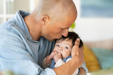 Mid erwachsenen Vater küsst sein Baby auf die Stirn im Wohnzimmer - SBOF03327