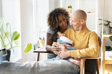 Happy parents with sleeping baby in living room - SBOF03347