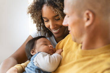 Happy parents smiling at their sleeping baby girl at home - SBOF03350