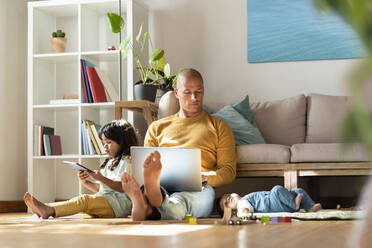 Vater arbeitet am Laptop, während er bei seinen Töchtern zu Hause sitzt - SBOF03372