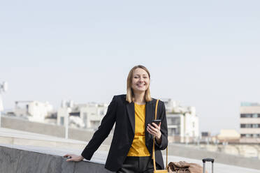 Smiling female entrepreneur standing with mobile phone - EIF00671