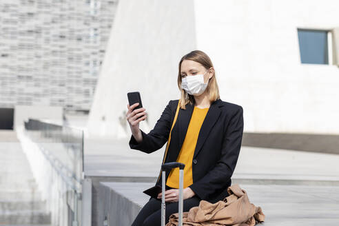 Unternehmerin mit Gesichtsmaske, die ein Selfie mit ihrem Mobiltelefon macht - EIF00675