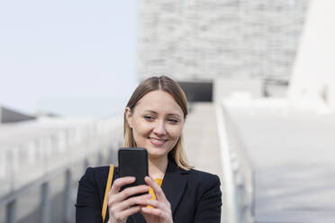 Mid adult businessman smiling while taking selfie through mobile phone - EIF00685