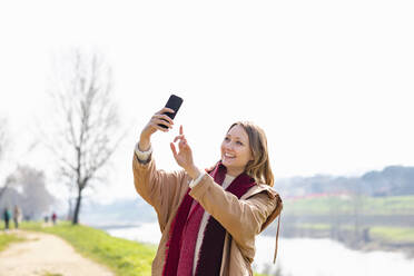 Glückliche Frau nimmt Selfie durch Mobiltelefon - EIF00690