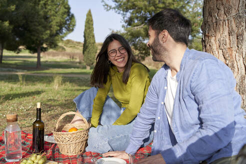 Cheerful woman looking at boyfriend during picnic - VEGF04076