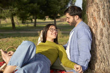 Smiling woman talking with boyfriend while relaxing in park during picnic - VEGF04087