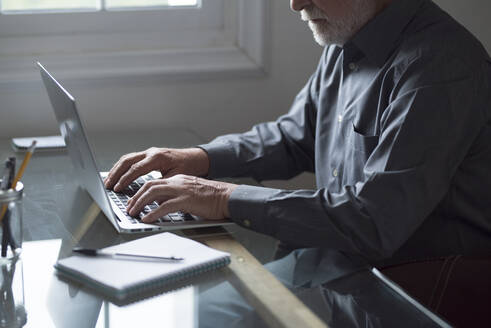 Älterer männlicher Geschäftsmann arbeitet am Laptop am Tisch - SIPF02293
