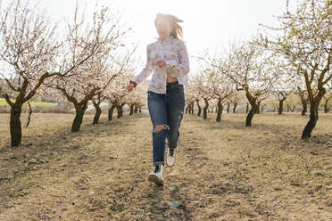 Lächelnde Frau läuft auf Mandelbäume zu - MGRF00188
