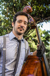 Handsome male musician holding double Bass - DLTSF01667