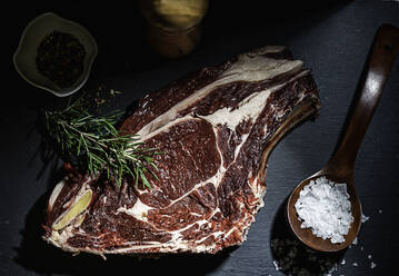 Raw steak, rosemary and salt on a serving board - CAVF93732