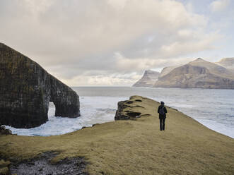 Frau beim Spaziergang in der Nähe von Drangarnir auf den Färöer Inseln - CAVF93742