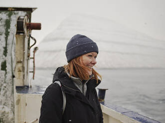 Woman on ferry looking out to mountains in the Faroe Islands - CAVF93746