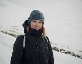 Porträt einer lächelnden Frau im Schnee, die in die Kamera schaut, auf den Färöer Inseln - CAVF93755