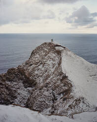 Zwei Menschen stehen am Rande einer verschneiten Klippe auf den Färöer-Inseln - CAVF93757