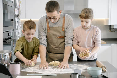 Mann und Kinder bereiten gemeinsam in der Küche Essen zu - AMPF00136