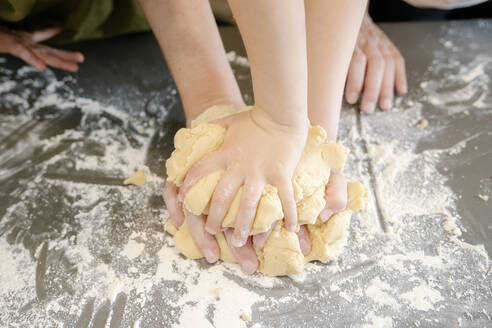 Vater und Kinder kneten mit den Händen Teig auf einer Kücheninsel - AMPF00138