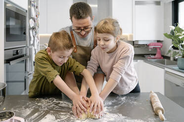 Kinder helfen Mann beim Kneten von Teig in der Küche - AMPF00140