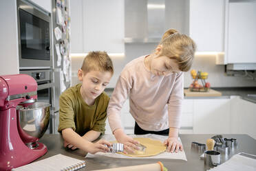 Mädchen und Junge verwenden Ausstechformen für Teig in der Küche - AMPF00142