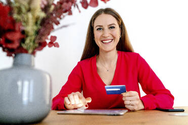 Smiling beautiful woman making card payment through digital tablet at table - OGF00985