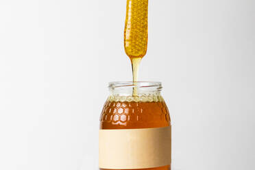 Stück Honigwabe auf einem Glas mit frischem, natürlichem, goldenem Honig mit weißem Hintergrund - ADSF22187