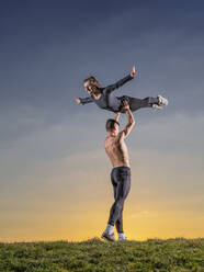 Man lifting woman while doing acrobats during sunset - STSF02887