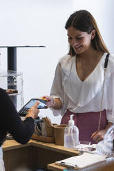Female entrepreneur paying through credit card at cafe - PNAF01004