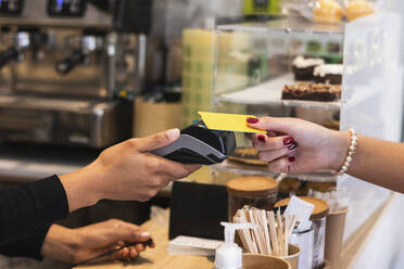 Woman paying through credit card at cafe - PNAF01030