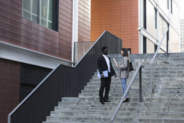 Geschäftsleute im Gespräch auf einer Treppe stehend - PNAF01032