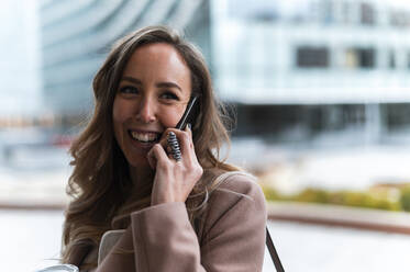 Lächelnde blondhaarige Geschäftsfrau, die mit einem Mobiltelefon spricht - JMPF00900