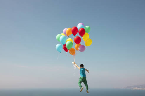Junge fliegt mit einem Bündel Luftballons in den Himmel - LJF02159