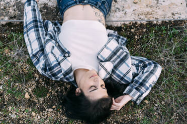 Entspannte Frau mit geschlossenen Augen im Gras liegend - DAMF00756