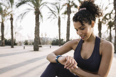 Female athlete checking time on wristwatch - XLGF01354