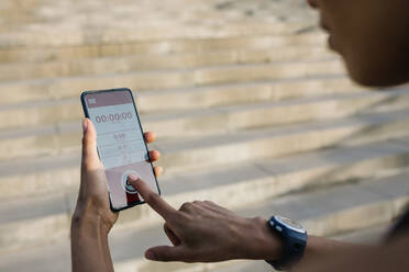 Sportlerin stellt Timer auf ihrem Smartphone ein - XLGF01363