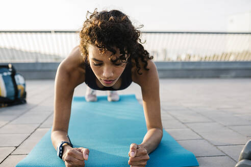 Weibliche Athletin beim Training in der Plank-Position auf einer Trainingsmatte - XLGF01366