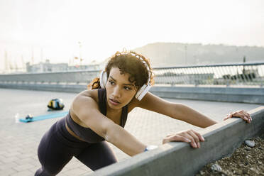 Sportswoman with headphones exercising on bridge - XLGF01371