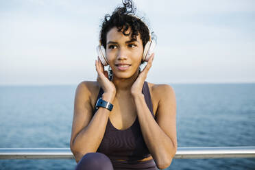Sportlerin hört Musik über Kopfhörer vor dem Meer - XLGF01375
