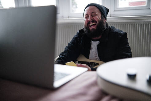 Älterer Mann mit Laptop lachend zu Hause - ASGF00083