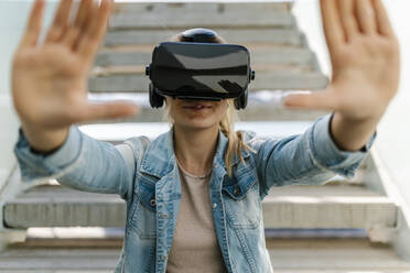 Frau gestikuliert beim Betrachten eines Videos in einem Virtual-Reality-Simulator - EGAF02086