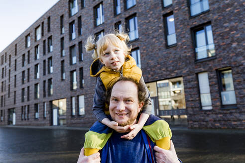Lächelnder Mann trägt seine Tochter auf der Schulter - IHF00420