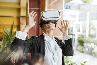 Female business professional with virtual reality simulator at hotel - LJF02176