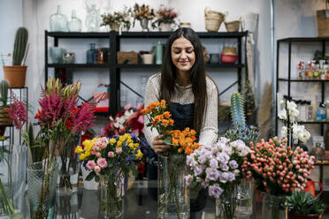 Young female florist arranging flowers at shop - EGAF02116