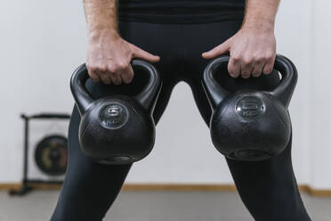 Mann hebt Kettlebells im Übungsraum - MGRF00200