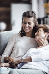 Smiling woman with grandmother relaxing on sofa - GUSF05499