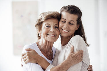 Fürsorgliche junge Frau, die ihre Großmutter zu Hause umarmt - GUSF05512