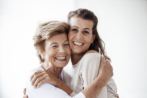 Cheerful senior woman embracing smiling granddaughter - GUSF05513