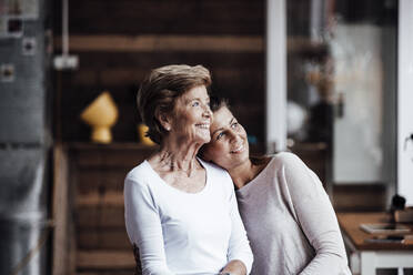 Smiling woman with head on shoulder of grandmother looking away - GUSF05527